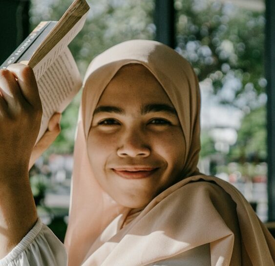 a woman in a hijab is holding a book
